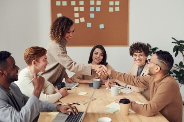 Team meeting at table and shaking hands